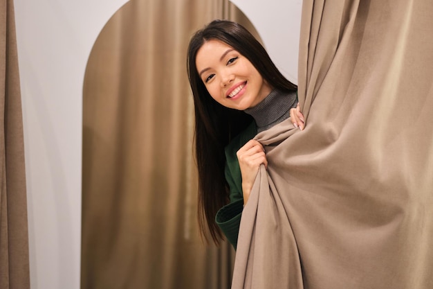 Photo gratuite belle fille asiatique souriante joyeusement lorgnant dans le dressing d'un magasin de mode moderne