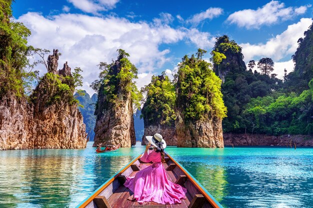 Belle fille assise sur le bateau et à la recherche de montagnes dans le barrage de Ratchaprapha au parc national de Khao Sok, province de Surat Thani, Thaïlande.