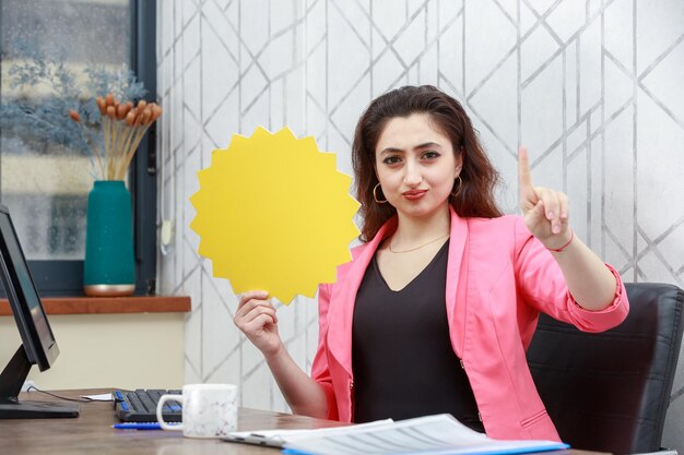 Belle fille assise dans le bureau tenant une bulle d'idée et leva le doigt Photo de haute qualité