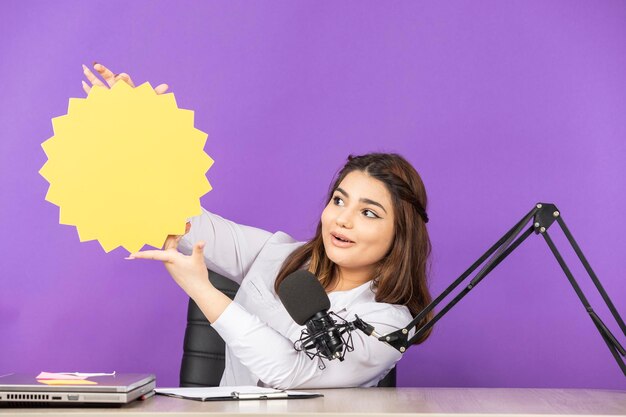 Belle fille assise derrière le bureau et tenant une bulle d'idée Photo de haute qualité