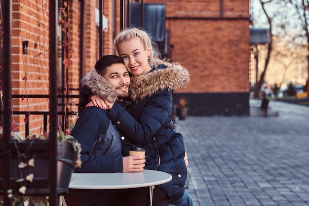 Photo gratuite belle fille assise sur les genoux de son petit ami passe du temps ensemble dans le café à l'extérieur.