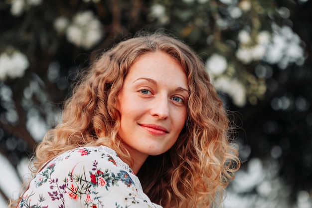 Belle fille assise et souriante en chemise texturée blanche pendant la journée.