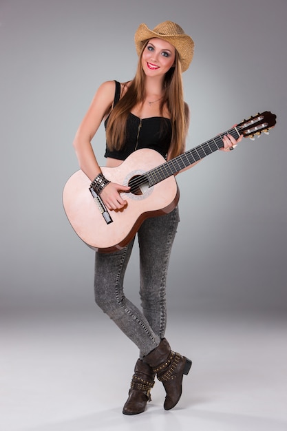 La belle fille au chapeau de cowboy et à la guitare acoustique.