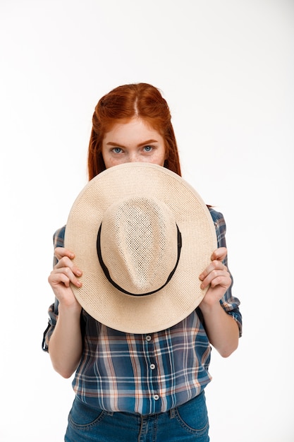 Photo gratuite belle fille au gingembre avec chapeau sur mur blanc.