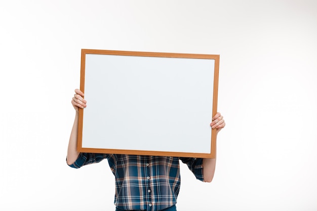 belle fille au gingembre avec tableau blanc sur mur blanc.