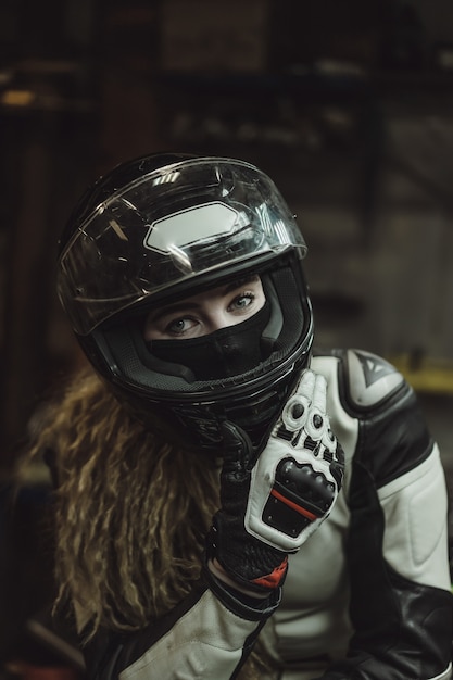 Photo gratuite belle fille aux cheveux longs dans le garage réparer une moto