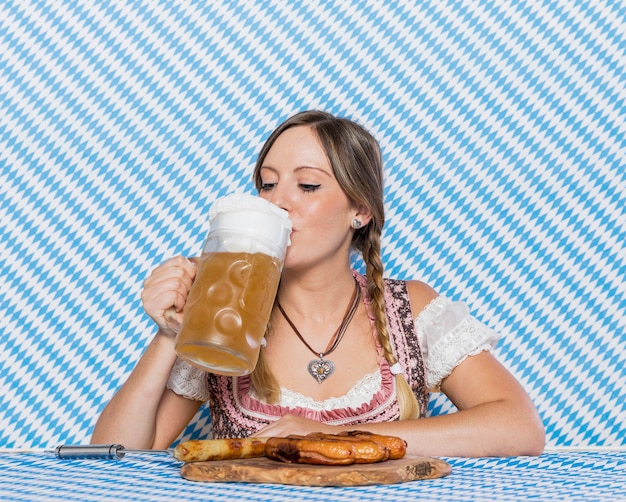 Belle fille bavaroise buvant de la bière