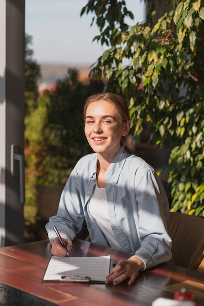 Photo gratuite belle fille blonde écrit sur un presse-papiers