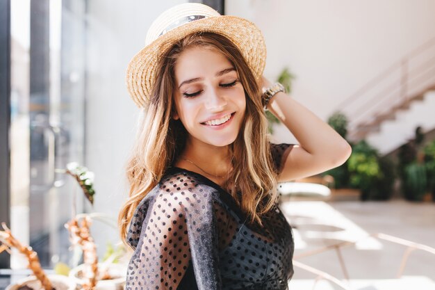 Belle fille blonde avec un grand sourire heureux posant dans une pièce lumineuse bénéficiant de bons souvenirs