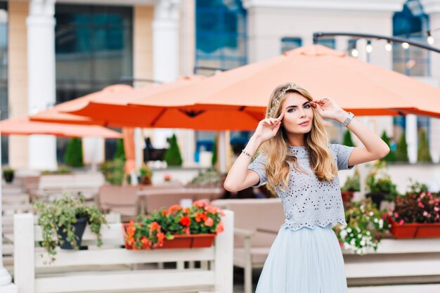 Belle fille blonde en jupe de tulle bleu marche sur fond de terrasse.