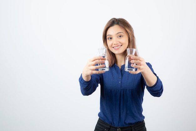 Belle fille en blouse bleue tenant un verre d'eau sur blanc.