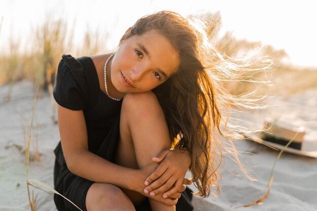 Belle fille brune enfant posant sur la plage Couleurs chaudes du coucher du soleil