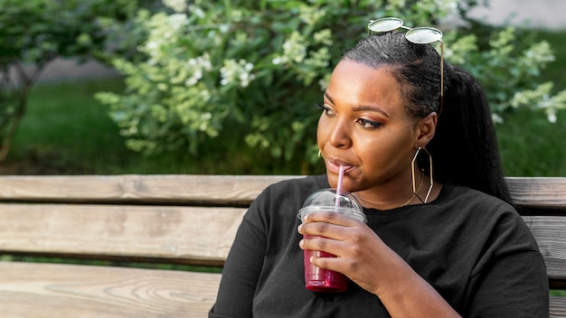 Belle fille buvant un smoothie à l'extérieur