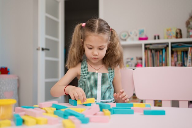 Belle fille caucasienne jouant avec des blocs multicolores en bois