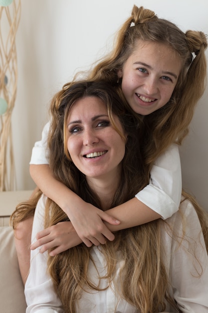 Belle fille en chemise blanche assise et souriante dans le salon.