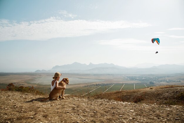 Belle fille avec et chien au sommet de la montagne