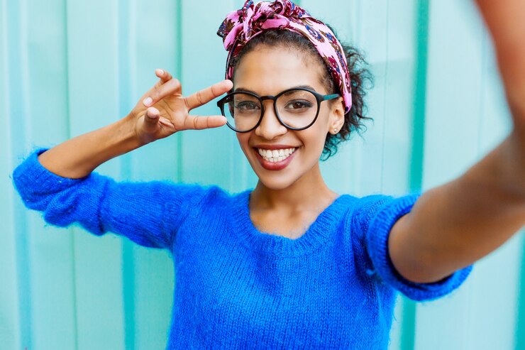 Photo gratuit belle fille avec une coiffure élégante faisant autoportrait par caméra sur turquoise