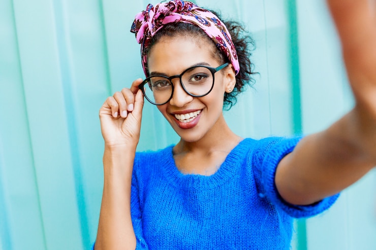 Photo gratuit belle fille avec une coiffure élégante faisant autoportrait par caméra sur turquoise