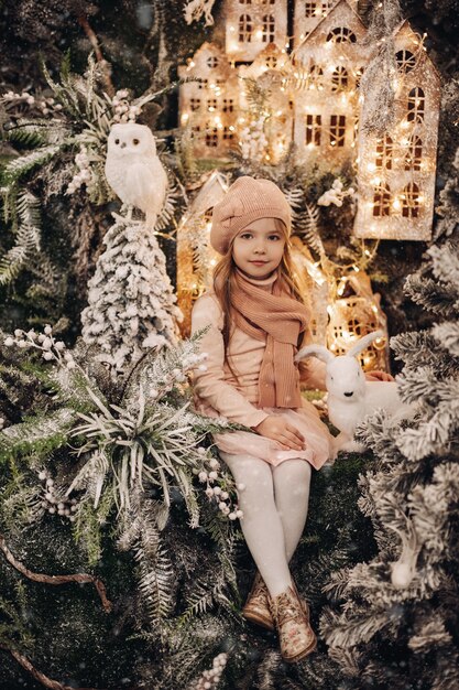 Belle fille dans une décoration de Noël avec beaucoup d'arbres sous la neige et les lumières