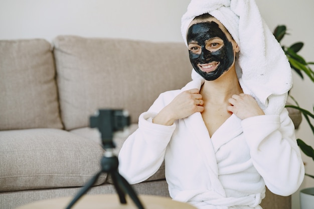 Belle fille dans un peignoir blanc à la maison enregistrer une vidéo