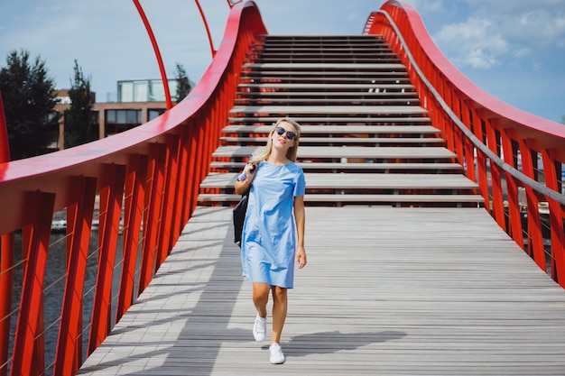 belle fille dans une robe bleue posant sur le pont