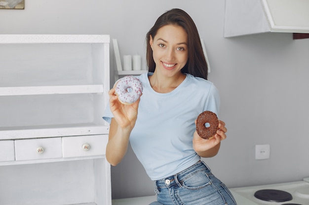 Belle fille debout dans une cuisine avec beignet