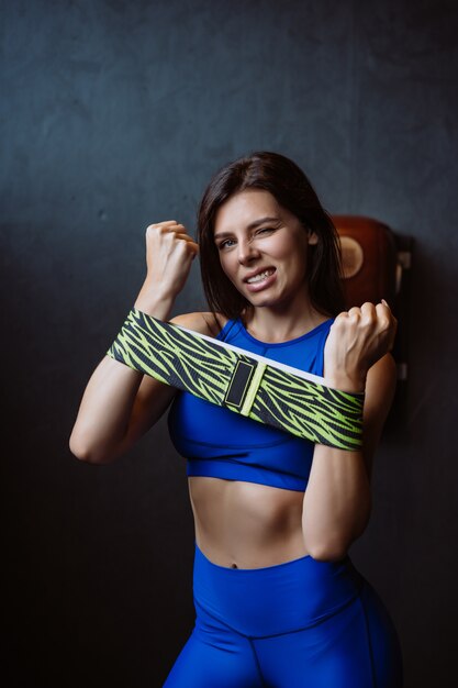 Belle fille avec une figure de sport se dresse sur un mur sombre et pose