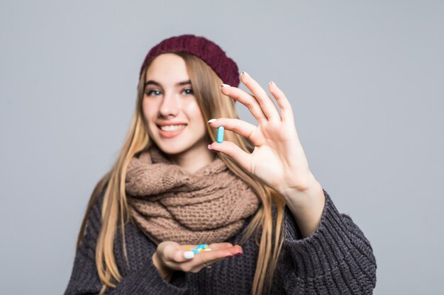 Belle fille avec la grippe ou le rhume a beaucoup de médicaments à prendre pour devenir en bonne santé sur le gris