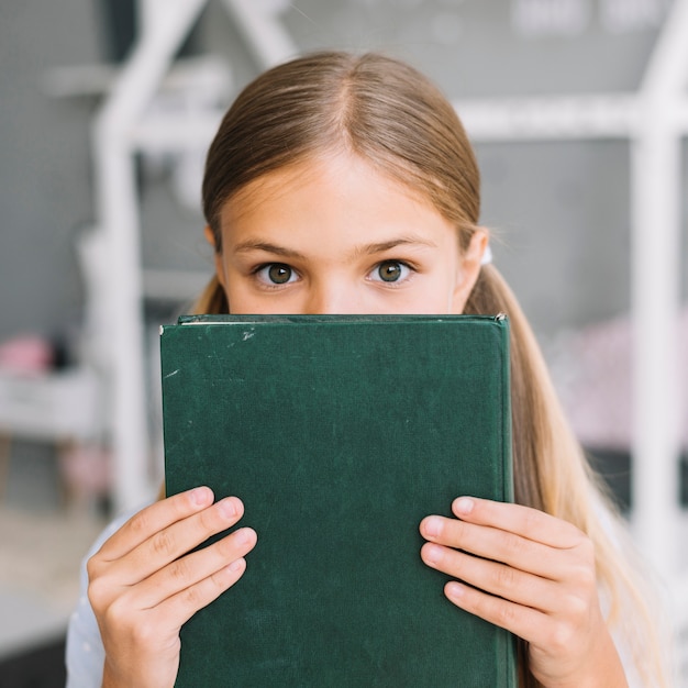 Belle fille heureuse posant avec un livre