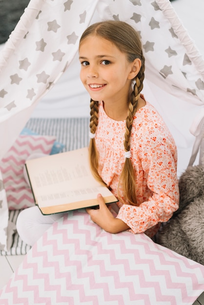 Belle fille heureuse posant avec un livre