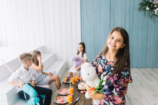 Photo gratuite belle fille avec des jouets et des fleurs lors de la fête d'anniversaire