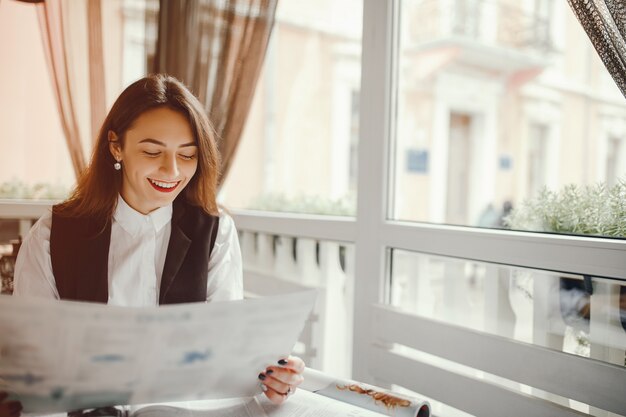 Une belle fille lit un magazine dans un café