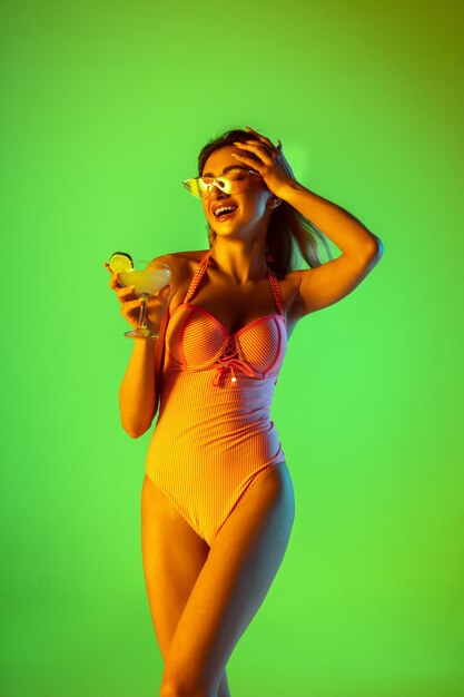 Belle fille en maillot de bain à la mode isolée sur dégradé en néon