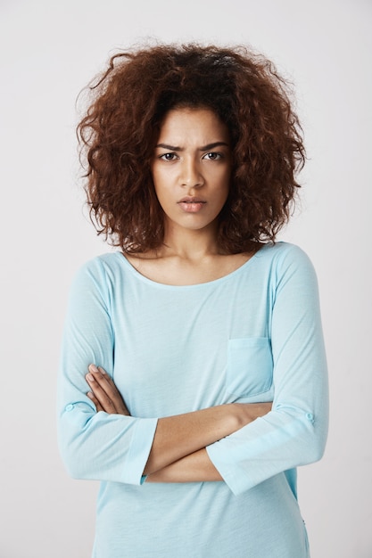 Belle fille mécontente regardant brutalement avec les bras croisés. Se quereller avec son petit ami après une longue nuit. Portrait de jeune femme en pyjama le matin.