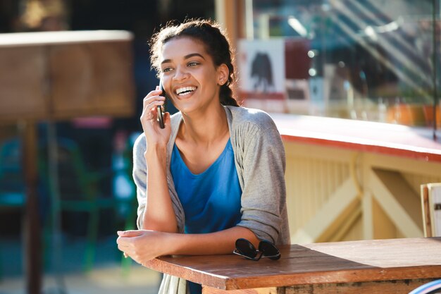 Belle fille à la peau sombre joyeuse a parlé au téléphone