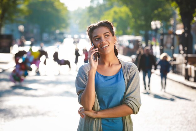 Belle fille à la peau sombre joyeuse a parlé au téléphone