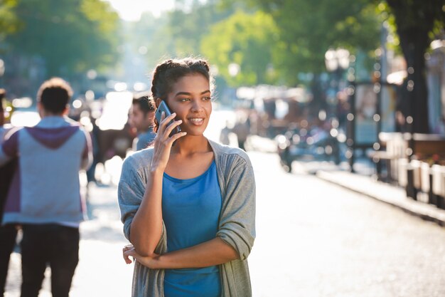 Belle fille à la peau sombre joyeuse a parlé au téléphone