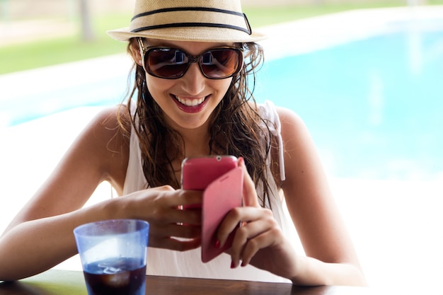 Belle fille prenant un téléphone mobile à la piscine.