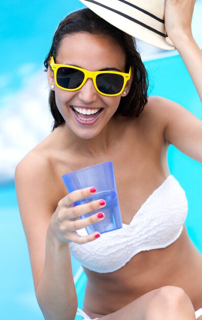 Belle fille qui boit de l&#39;eau à la piscine.