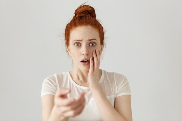 Belle fille rousse avec noeud de cheveux ayant un regard effrayé et effrayé