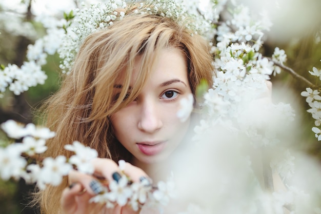 Belle fille se promène dans le jardin luxuriant vêtue d'une couronne