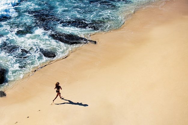 Belle fille se promène le long de la plage sauvage. vue de dessus incroyable.