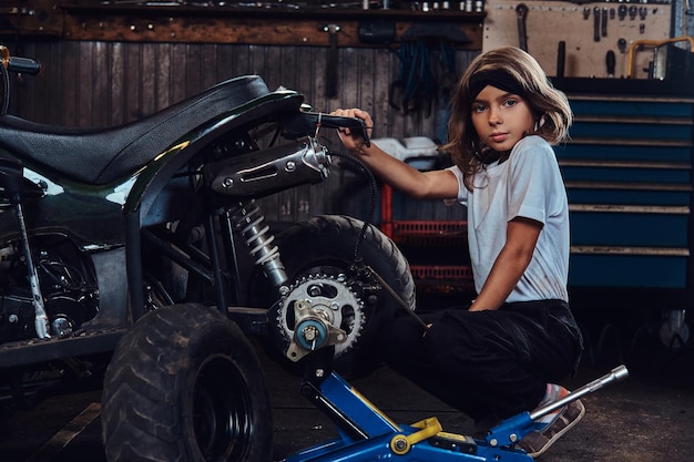 Une belle fille sérieuse veut être technicienne automobile quand elle sera grande, elle essaie de réparer un VTT cassé.