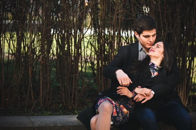 Belle fille et son petit ami reposant ensemble sur un banc dans le parc