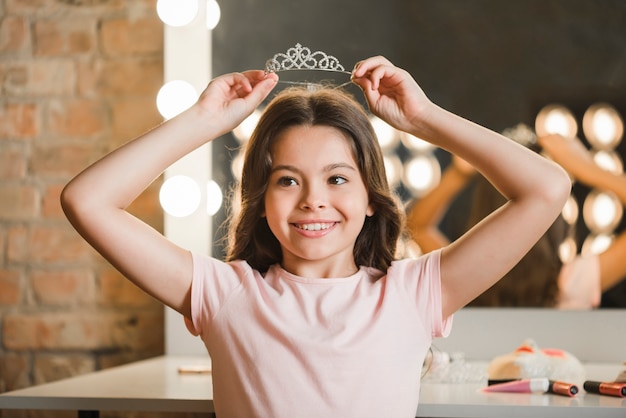 Belle fille tenant une couronne de diamant sur sa tête