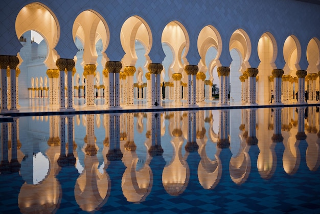 Belle galerie de la célèbre mosquée blanche sheikh zayed à abu dhabi, émirats arabes unis. reflets au coucher du soleil