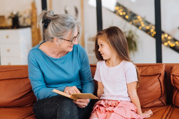 Belle grand-mère de femme âgée lisant une histoire à sa petite-fille.