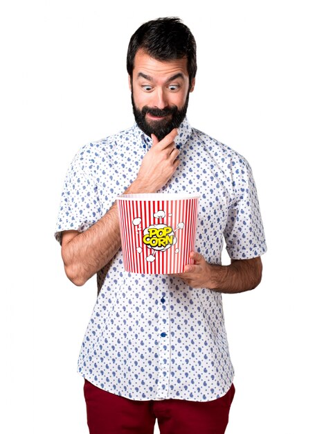 Belle homme brune à la barbe mangeant des popcorns