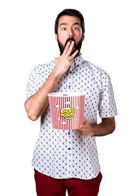 Belle homme brune à la barbe mangeant des popcorns