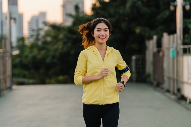 Belle jeune athlète d'Asie exécutant des exercices d'entraînement en milieu urbain. Teen girl japonaise portant des vêtements de sport sur le pont de la passerelle en début de matinée. Mode de vie sportif actif en ville.